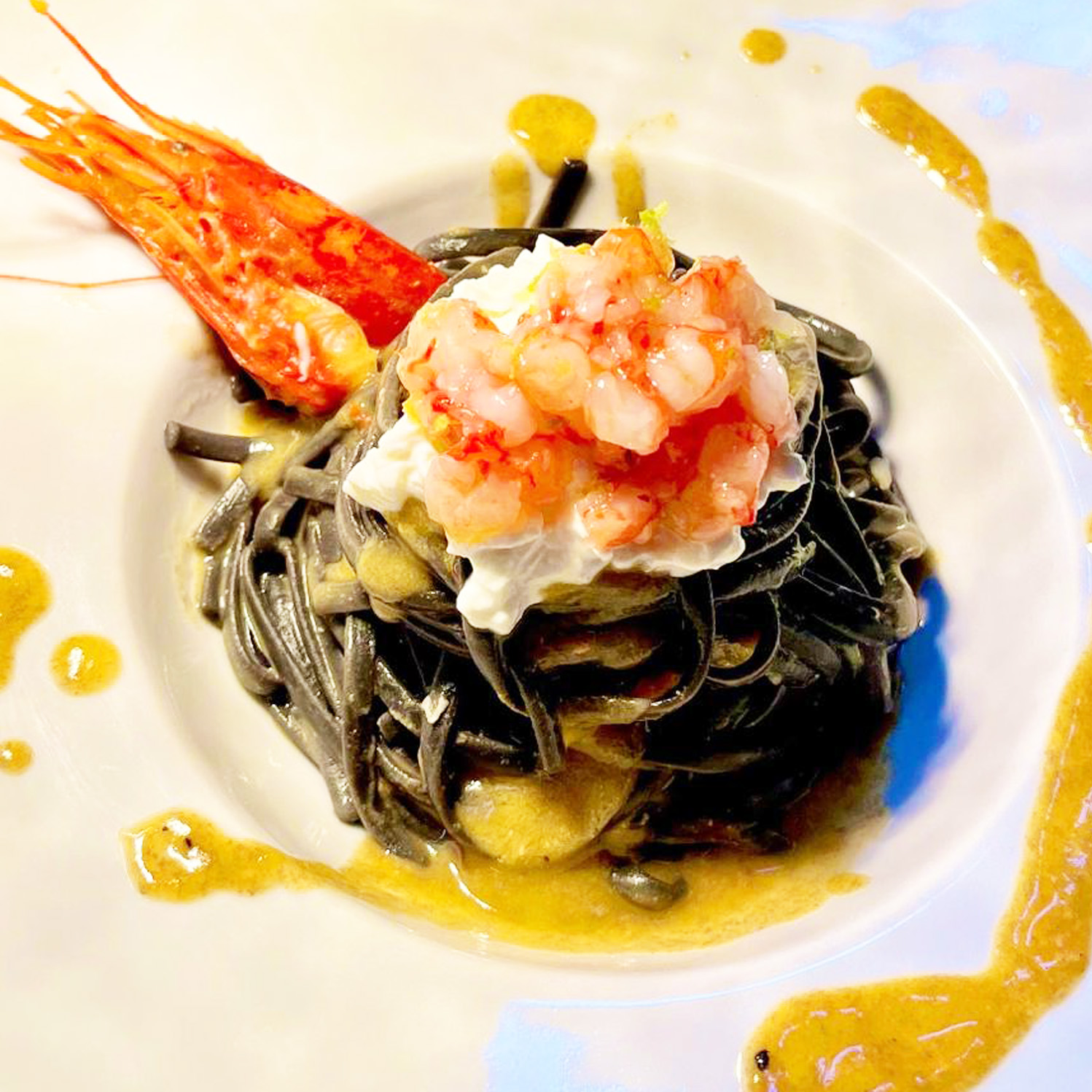 Linguine with cuttlefish ink, stracciata of burrata, red prawn tartare flavored with lime
